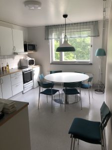 Runt köksbord med stolar, spis, micro och arbetsbänk.
