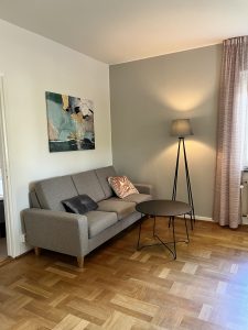 Vardagsrum med soffa och lampa.