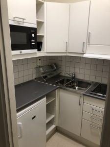 Kök med spishäll, vask och skåp.