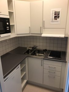 Kök med spishäll, vask och skåp.