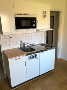 Köksbänk med vask, ugn och skåpsinredning. 