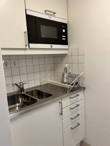 Kök med diskbänt, micro och köksskåp.