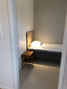 Sovrum med lampa och sängbord.