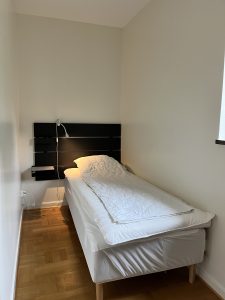 Sovrum med säng, lampa och sängbord.