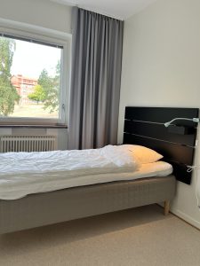 Sovrum med säng, lampa och fönster.