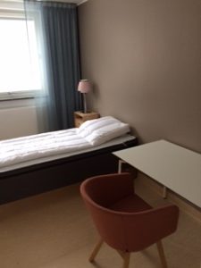 Sovrum med säng, skrivobord och fåtölj.