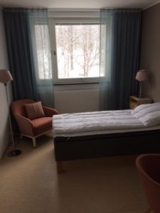 Sovrum med säng, fåtölj, fönster.